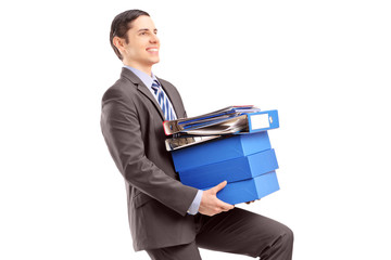 Young businessman carrying heavy folders