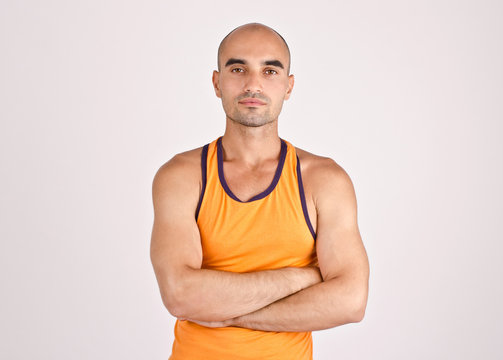 Portrait of a fit athletic bald man with arms crossed.