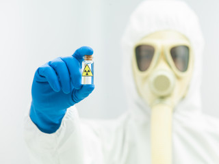 person in protective suit holding isotope sample
