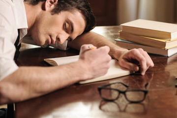Tired of overworking. Handsome young author sleeping at the tabl