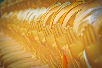 Row of golden Buddha statues in praying position