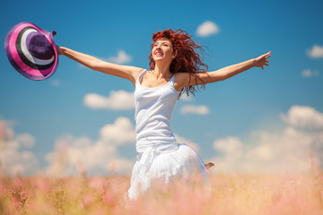 Cute woman running in the field with flowers