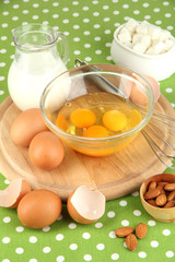 Broken egg in bowl and various ingredients next to them