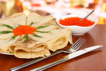 Delicious pancakes with red caviar on table in cafe