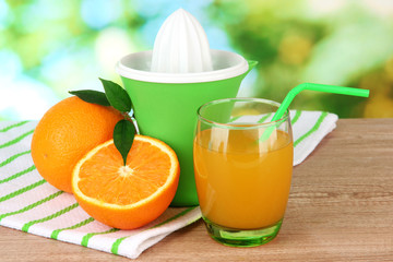 Citrus press, glass of juice and ripe oranges
