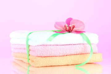 Obraz na płótnie Canvas Towels tied with ribbon on light pink background