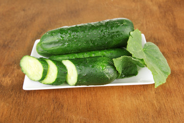 Tasty green cucumbers on color napkin, wooden background