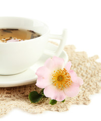 Cup of herbal tea with hip rose flowers, isolated on white