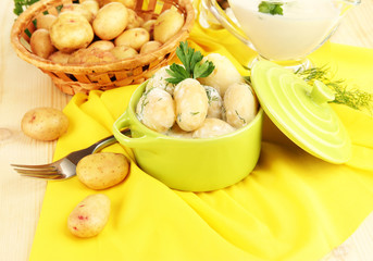 Tender young potatoes with sour cream and herbs in pan