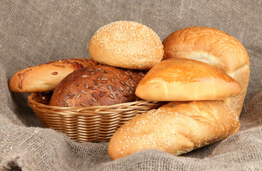 Baked bread in wicker basket on burlap background