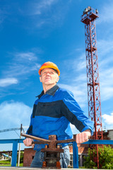 Senior man in working uniform with pipe valve. Looking fare away