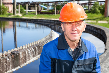 Senior hard worker sitting near water filtration unit. Copyspace