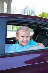 Happy Caucasians little girl smiling of a car