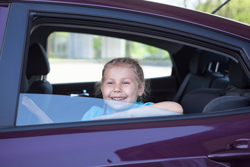 Happy smiling Caucasian girl sitting inside of car