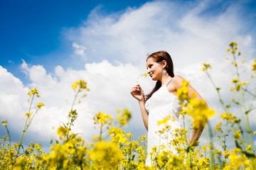 Beautiful Woman in white dress holding a rape flower. Rape Field - 53680377