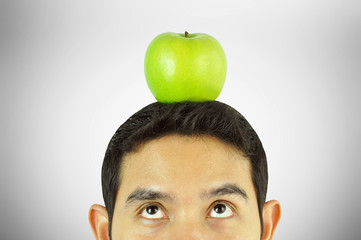 Young man looking up to apple on his head