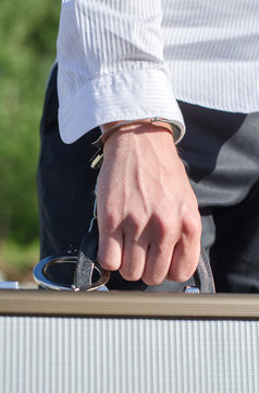 Close up view of male hand enchained to suitcase