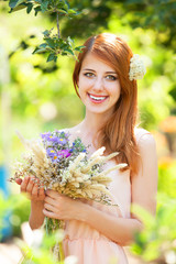 Naklejka premium Redhead girl with flowers at outdoor.