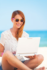 Cute woman with white laptop on the summer beach