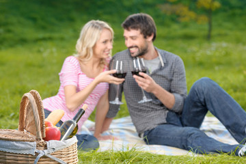 Cheers! Loving young couple enjoying wine on a picnic together
