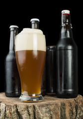Bottles of beer and beer mug on stump