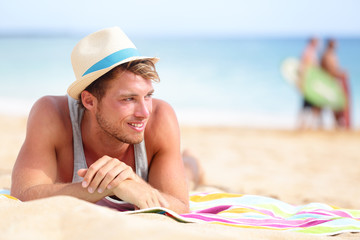 Man on beach lying in sand looking to side