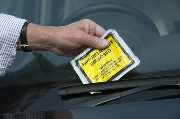 Man's hand & penalty notice on car
