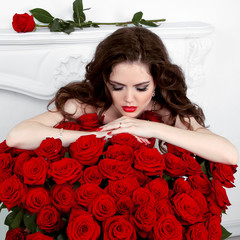 Young beautiful woman leaning on the red roses bouquet. Valentin