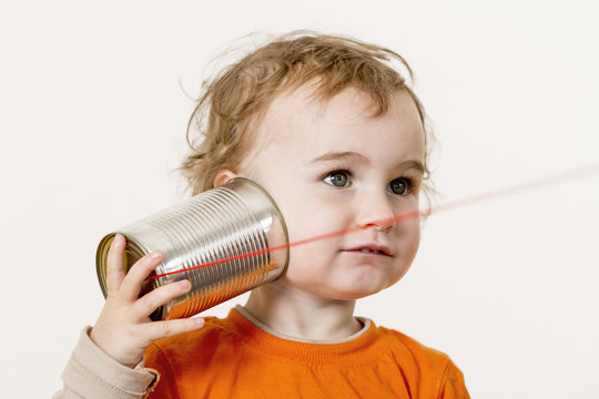 young child listening to tin can phone