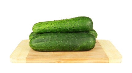 Tasty green cucumbers on wooden cutting board, isolated on