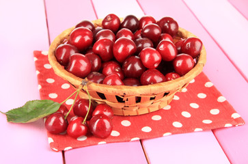 Cherry berries in wicker basket on wooden table close-up