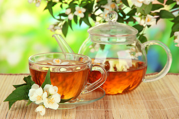 Cup of tea with jasmine, on bamboo mat, on bright background
