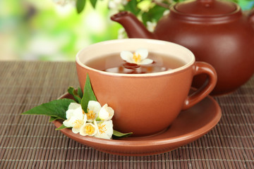 Cup of tea with jasmine, on bamboo mat, on bright background
