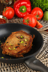 Piece of fried meat on pan on wooden table close-up