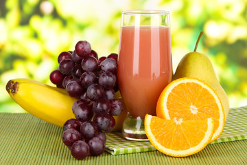 Glass of fresh juice on table on bright background