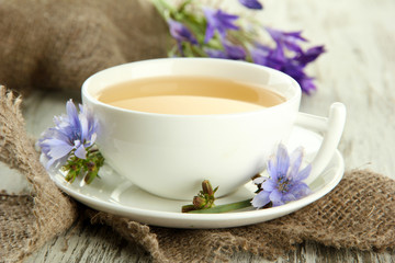 Cup of tea with chicory, on wooden background