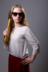 Portrait of a beautiful girl in sunglasses holding a clutch