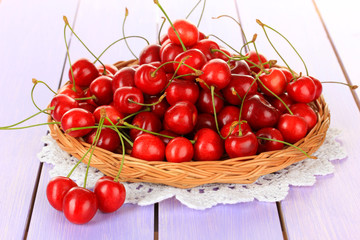 Cherry berries in wicker basket on wooden table close up