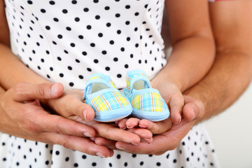 Obraz premium Young married couple with baby clothes on grey background