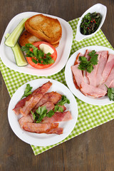 Bacon on plates on napkin on wooden table