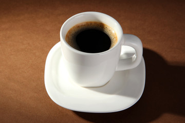 Fototapeta na wymiar Cup of coffee on brown background