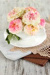 Roses in cup on napkins on  wooden background