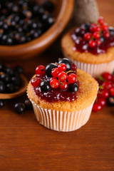 Tasty muffins with berries on wooden table