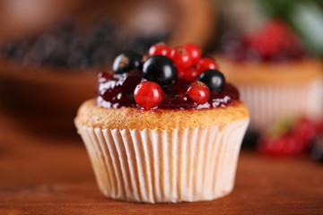 Tasty muffin with berries on wooden table
