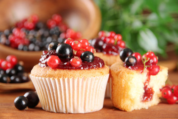 Tasty muffins with berries on wooden table