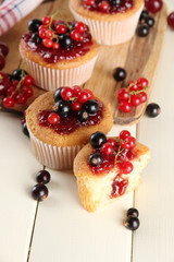 Tasty muffins with berries on white wooden table