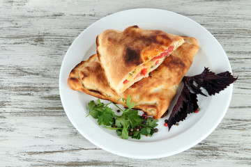Pizza calzones on plate on wooden table