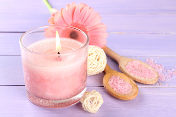 Beautiful pink candle with flower on purple wooden background
