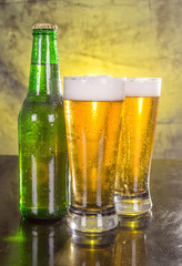 Glasses of beer with green bottle