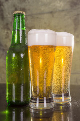 Glasses of beer with green bottle